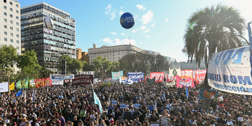 Eine Menschenmenge mit Plakaten, im HIntergrund schwebt ein großer Ballon