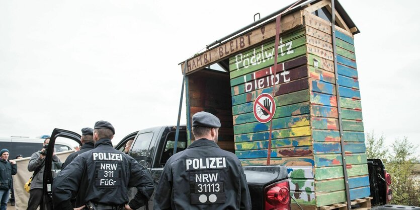 Einsatzkräfte der Polizei stehen neben einem auf einen Wagen geladenen Bretterhaus aus dem Hambacher Forst, 7. Oktober 2018