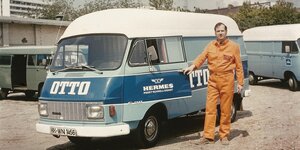 Ein Paketbote in orangefarbener Arbeitskleidung steht vor einem Lieferwagen, historische Aufnahme aus den 760er Jahren