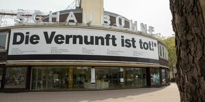 Ein Theaterhaus von außen, auf einem großen Banner steht 