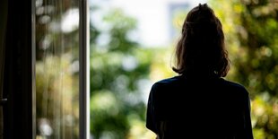 Frau steht am offenen Fenster