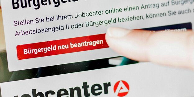 Eine Frau tippt auf einem Tablet auf einen Link zum Beantragen des Bürgergeldes im Kundenbereich im Jobcenter