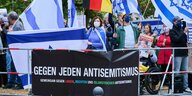 Personen auf einer Demonstration halten Schilder hoch, die sich gegen Antisemitimus aussprechen