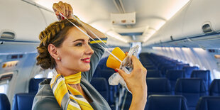 Stewardess zeigt Sauerstoffmaske