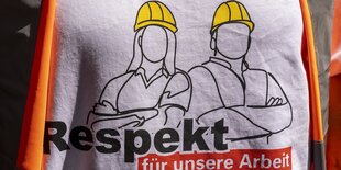 Detailaufnahme eines T-shirts mit dem Aufdruck einer Zeichnung von einem Bauarbeiter und einer Bauarbeiterin