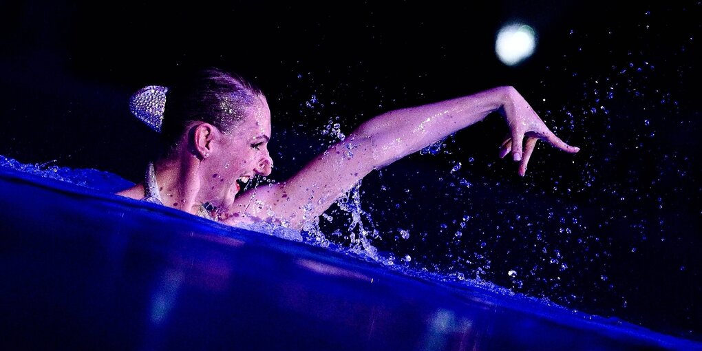 Synchronschwimmerin Swetlana Romaschina streckt Kopf und Arm aus dem Wasser