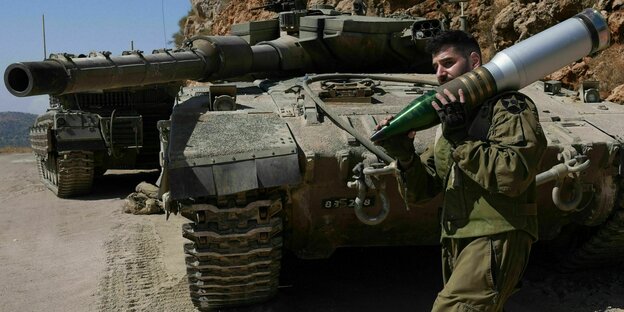 Ein israelischer Reservesoldat trägt eine Panzergranate in einem Panzerkampfgebiet nahe der nordisraelischen Grenze zum Libanon