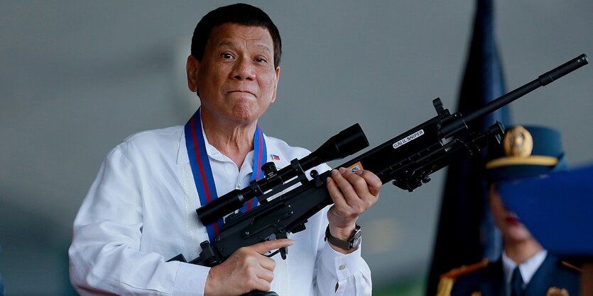 Rodrigo Duterte hält ein gewehr in den Händen