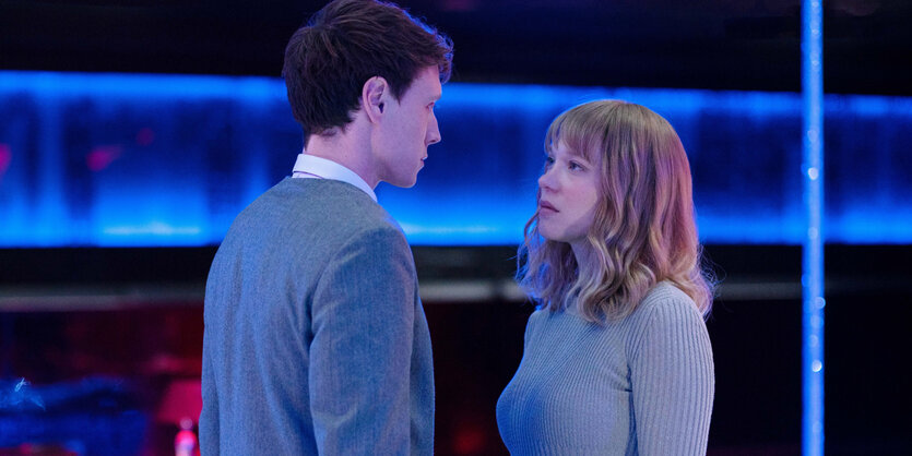 Louis Lewanski (George MacKay) und Gabrielle Monnier (Léa Seydoux) stehen sich steif vor einer neonbeleuchteten Kulisse gegenüber.