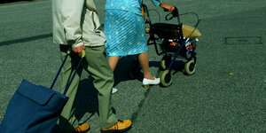 Ein und Mann und eine Frau sind hüftabwärts zu sehen, beide schieben einen Einkaufstrolley