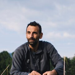 Tassos Shialis hat kurze dunkle Haare, einen dunklen Dreitagebart und trägt einen Pulli mit Reisverschluss am Kragen