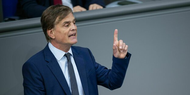 Bernd Baumann hebt dne Zeigfinger im Bundestag. er trägt einen dunklen Anzug und eine dunkle Krawatte auf einem hellen Hemd.