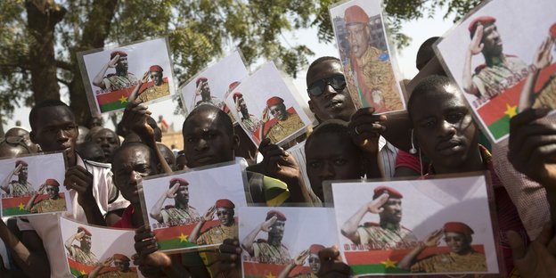 Auf dem Bild sind junge Burkinabé zu sehen, die Fotos von Sankara und dem ehemaligen Präsidenten Isaac Zida zeigen.