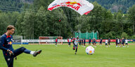 Gelandeter Fallschirmspringer kickt gegen den Ball