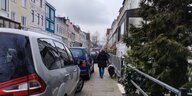 Mensch mit Hund auf einem zuparkten Gehweg in der Bremer Neustadt