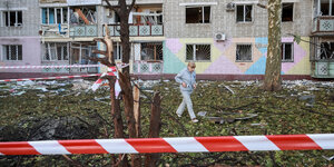 Eine Frau vor einer zerstörten Hausfassade