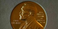 Bronze-goldene Nobelmedaille auf der das Gesicht von Alfred Nobel, dem Gründer des Nobelpreises zu sehen ist.