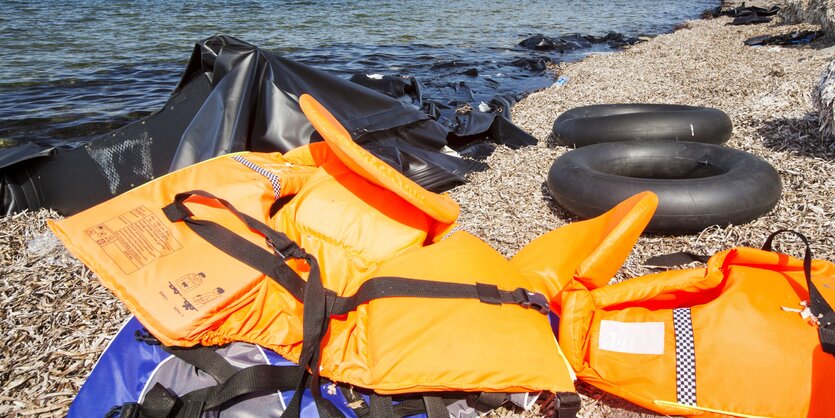 Schwimmwesten , PALSTIKBOOTRESTE und Rettungsringe liegen am STrand