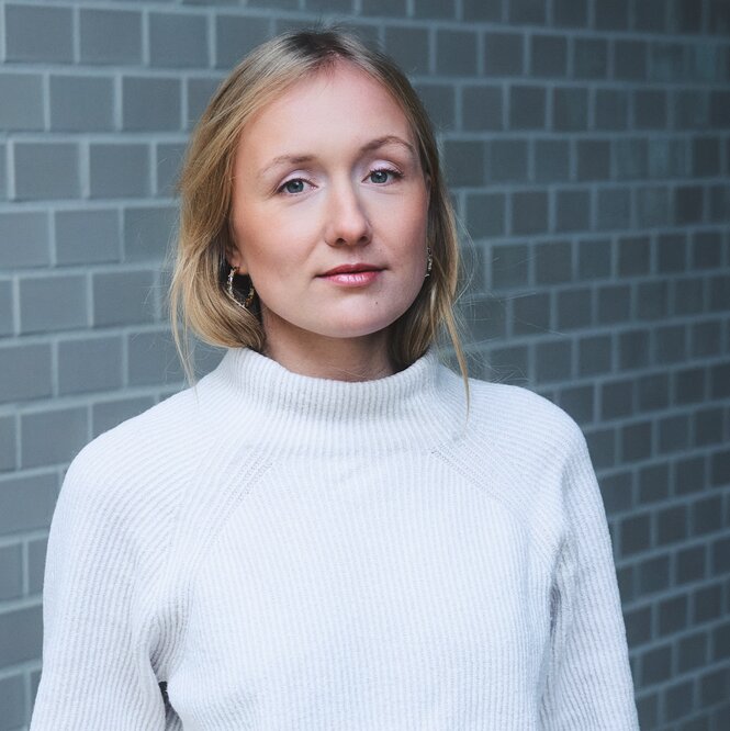 Frau mit blonden Haaren und weißem Pullover