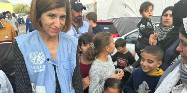 UNRWA-Sprecherin Juliette Touma bei einem Besuch in Gaza, mit blauer Weste der Organisation, von Frauen und Kindern umringt