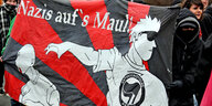 Demo-Banner auf dem steht "Nazis aufs Maul". Abgebildet sind die Umrisse von zwei Personen sowie eine Antifa-Fahne