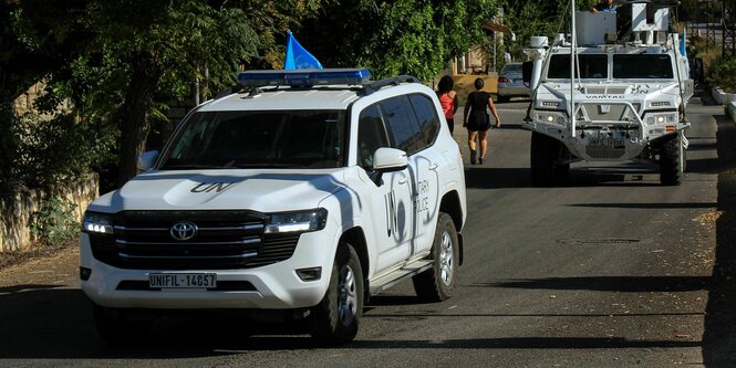 Weiße Autos mit blauen Fähnchen fahren in einem Konvoi