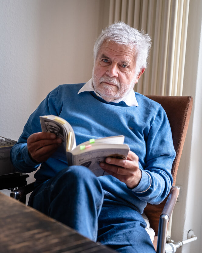 Frank Nonnenmacher sitzt mit einem Buch am Tisch.