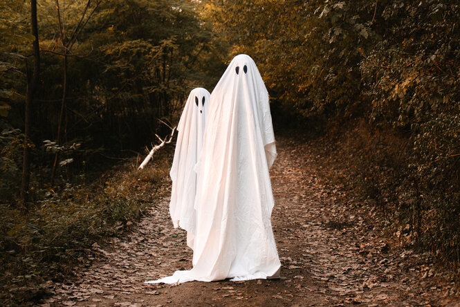 Zwei Personen als Gespenster verkleidet auf einem Waldweg im Herbst