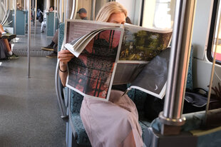 Eine Person ließt in der S-Bahn eine Zeitung