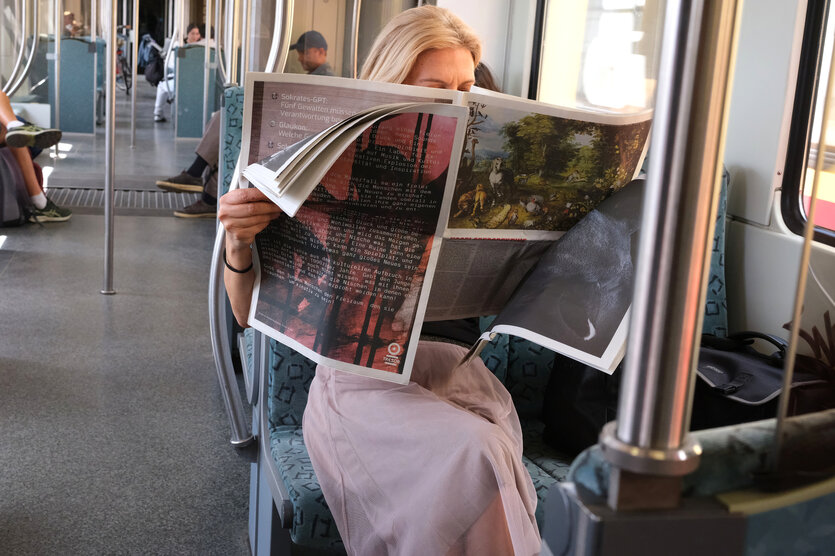 Eine Person ließt in der S-Bahn eine Zeitung