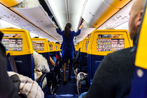 Eine Stewardess verschließt die Gepäckfächer in einem Flieger von Ryanair.