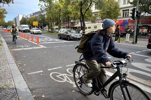 Eine Person fährt auf einem Fahrrad auf einem geschützten Radweg entlang einer großen Straße