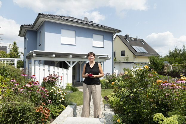 Cornelia Ernst steht vor ihrem Einfamilienhaus,vor dem ein schöner Garten mit Stauden angelegt ist