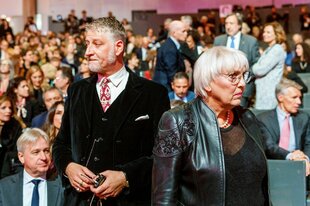 Alessandro Giuli und Claudia Roth stehen gemeinsam mit dem Rücken zum Publikum