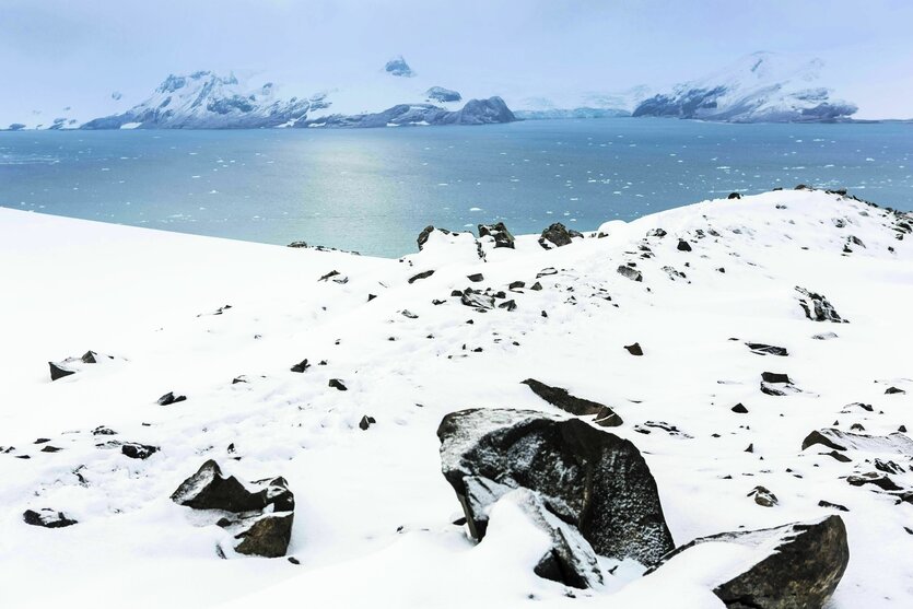 Landschaftsbild mit Eisbergen, blauem Wasser und verschneiten Steinlandschaften