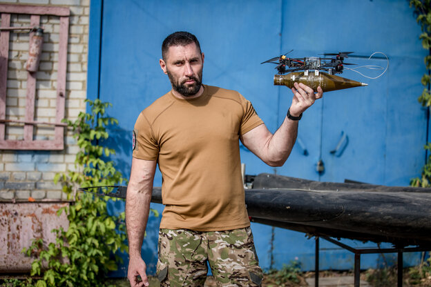 Ein Mann in Armeekleidung hält eine russische Drohne in der Hand