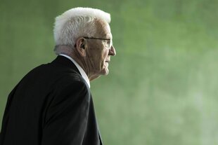 Winfried Kretschmann im Profil vor einer grünen Wand