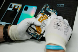 Behandschuhte Hände, die ein Smartphone reparieren