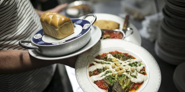 Im Restaurant Nanuchka in Tel Aviv balanciert ein Kellner drei Teller