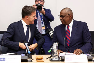 Zwei Männer schauen sich und sitzen an einem Konferenztisch.