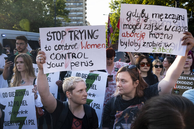 Frauen halten auf einer Demonstration Plakate in Polnisch und Englisch hoch