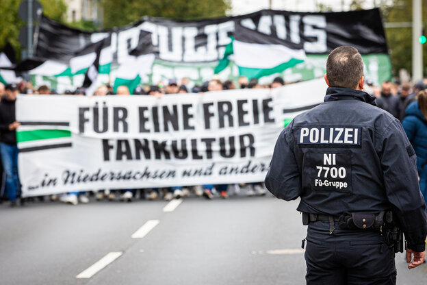 Ein Polizist steht vor einer demonstrierenden Menschenmenge