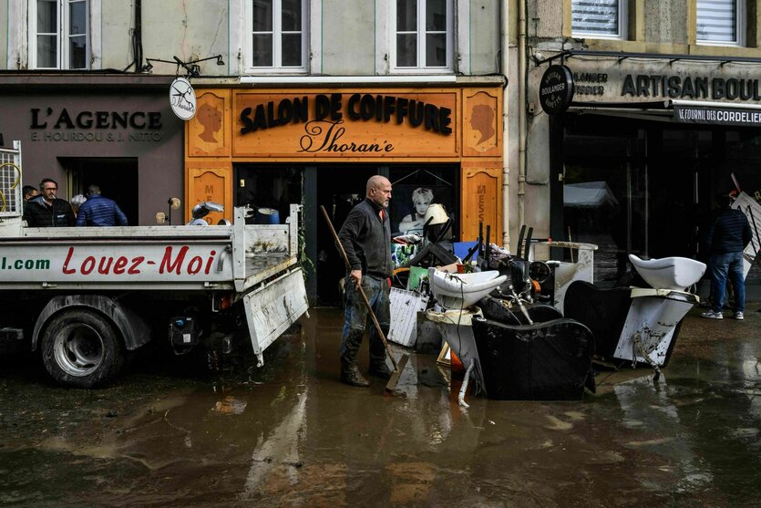 Ein Mann räumt einen Tag nach den Überschwemmungen in der Stadt Annonay in Zentralfrankreich, Schlamm und beschädigte Möbel vor einem Geschäft in einer Straße weg