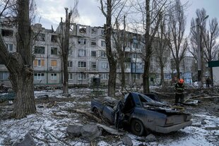 Ein Rettungsarbeiter räumt die Trümmer eines Wohnhauses weg, das durch eine Rakete zerstört wurde.