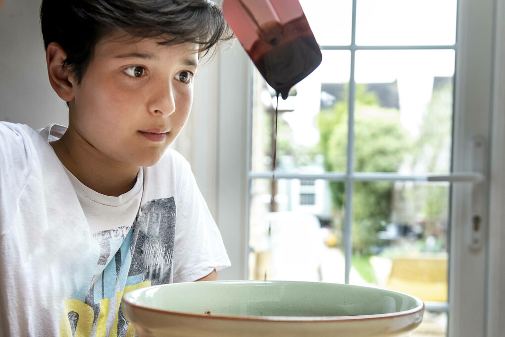 Ein Junge sitzt am Küchentisch und backt Schokoladenkuchen