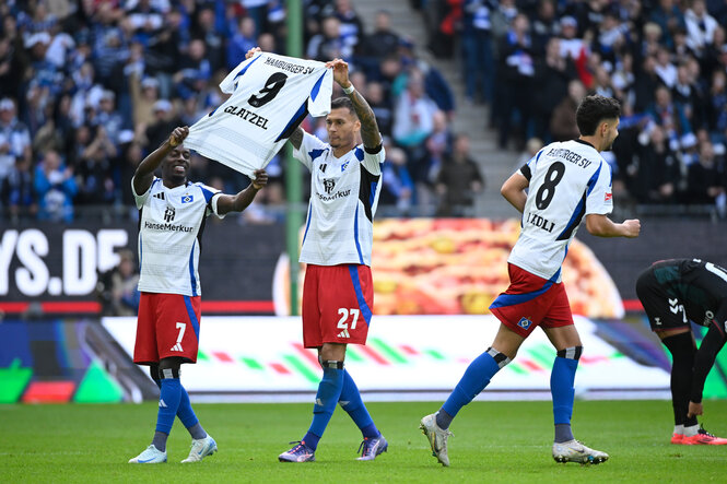 Zwei Fußballspieler halten ein Trikot hoch, auf dem der Name "Glatzel" zu lesen ist