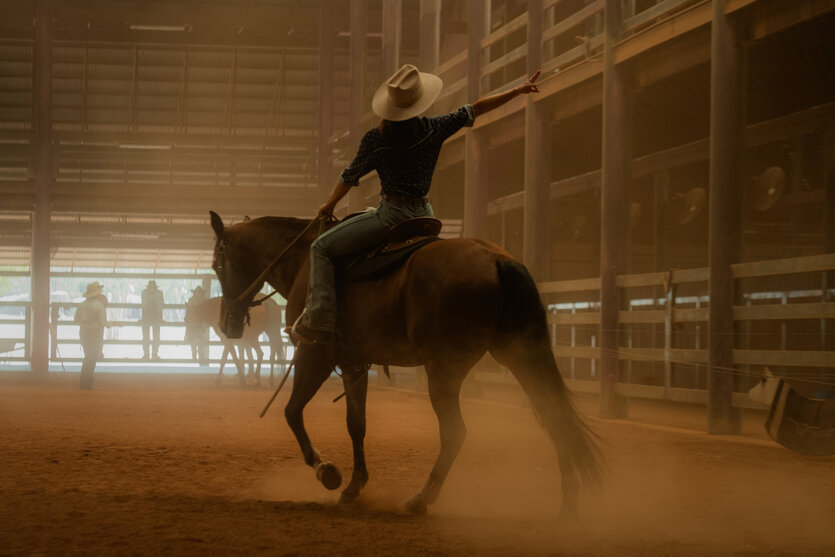 Ein Cowboy reitet ein Pferd in einer Reithalle