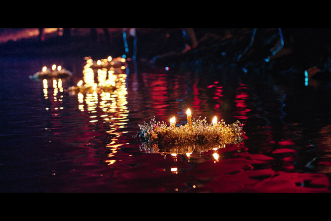 Ein Kreis brennender Kerzen treibt auf einem Fluss