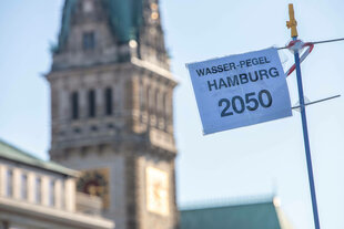 Ein Schild warnt vor hohem Wasserpegel am Hamburger Rathaus