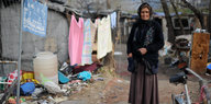 Eine ältere Frau steht auf einer Straße, an einer Wäscheleine hängt Kleidung